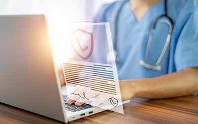 Medical worker typing on laptop.